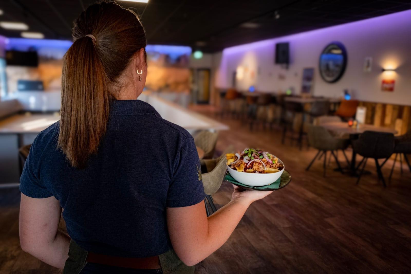 Medewerker brengt een gerecht naar tafel in de brasserie