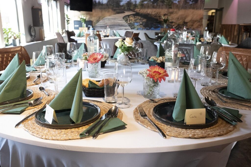 Feestelijk gedekte ronde tafel met groene servetten