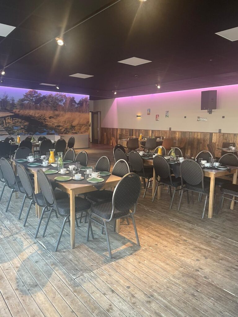 De zaal met lange gedekte tafels